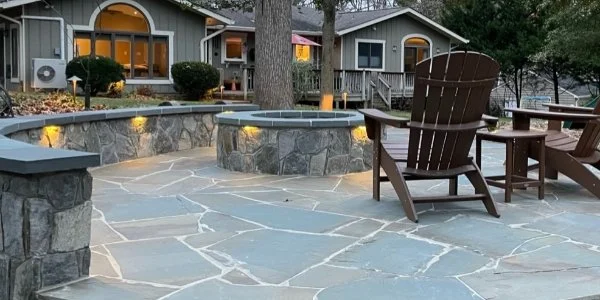 Outdoor living space in Alexandria, VA with a stone patio, fire pit, and seating wall.